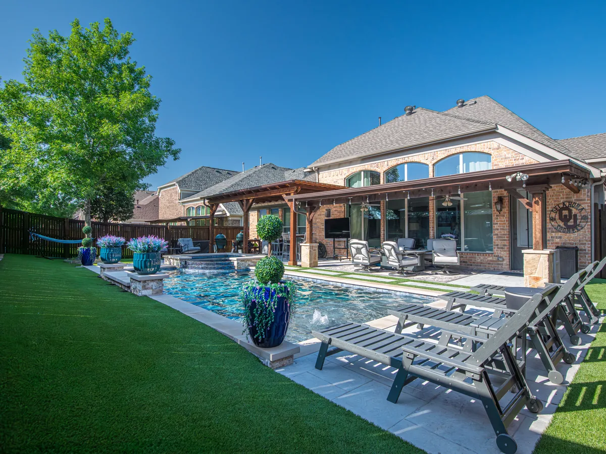 Backyard with synthetic grass beside a pool
